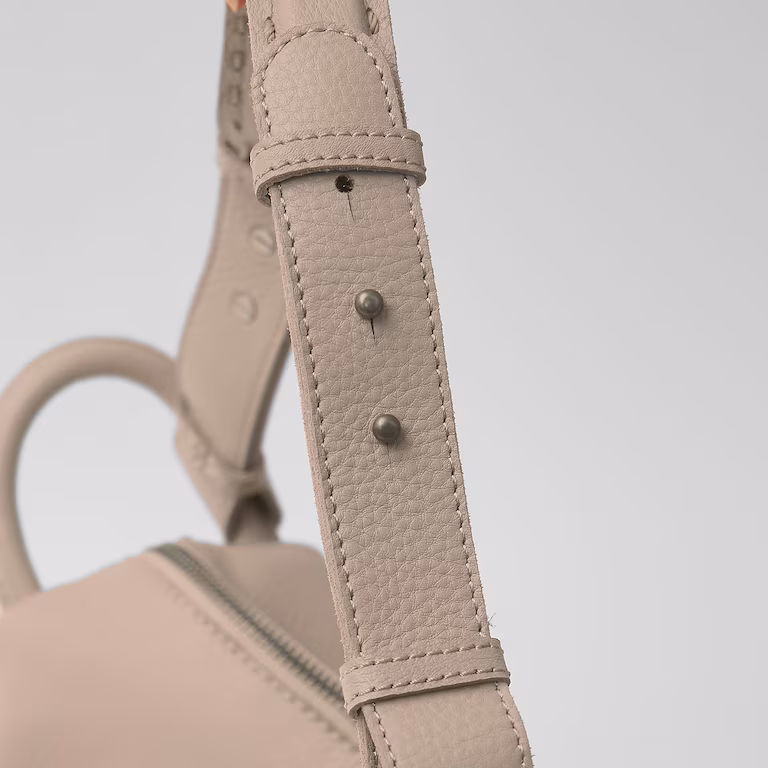 Close-up of a beige leather handbag strap with buckle details