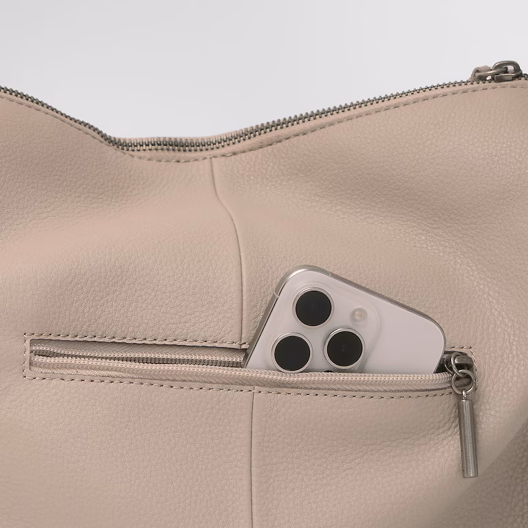 Smartphone in the pocket of a beige purse