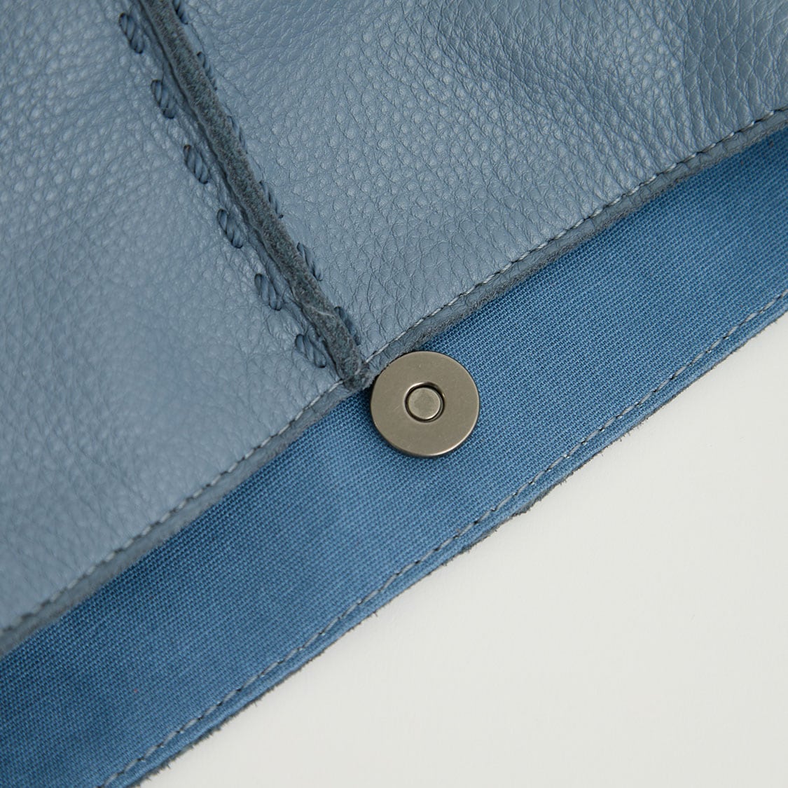 Close-up of a metal snap button on a blue fabric or material