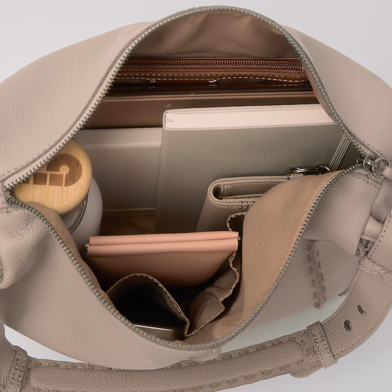 Open beige handbag containing books, a laptop, and personal items