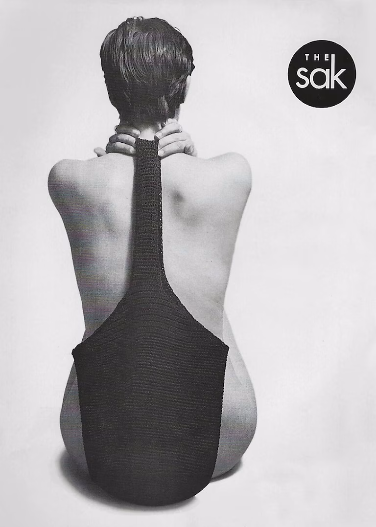 Black and white advertisement showing a woman's back, she's holding a purse strap over her shoulder