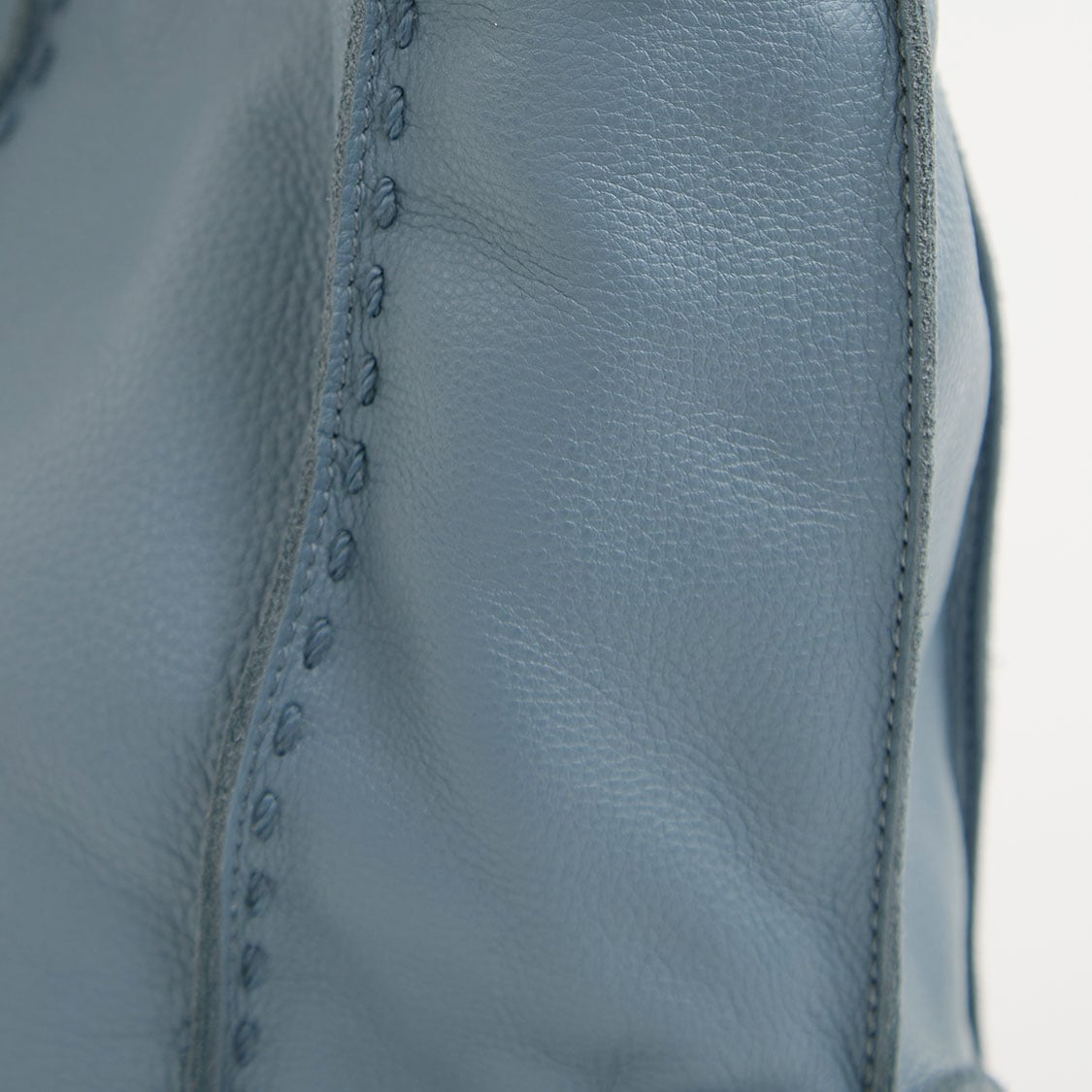 Close-up of blue textured leather material with stitching detail